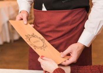 Cliente controlla un menù con prezzi non esposti prima di pagare il conto in un ristorante