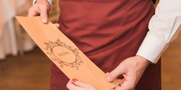 Cliente controlla un menù con prezzi non esposti prima di pagare il conto in un ristorante